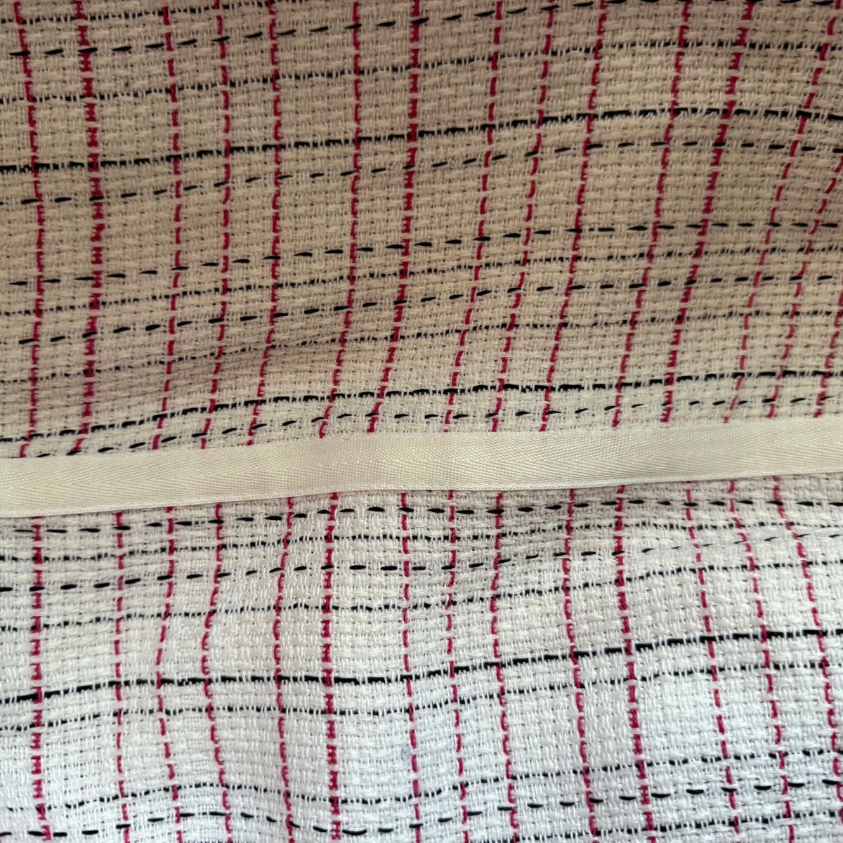 Close-up of fabric with red, black, and beige plaid pattern