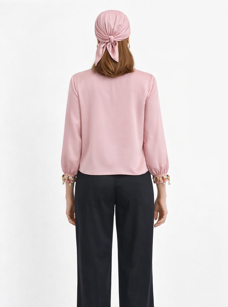 Pale rose Armani satin tie-front crop top with hand-applied shell and bead cuffs, worn with black wide-leg trousers — Bardees Riad Tie Crop (توب رياض).